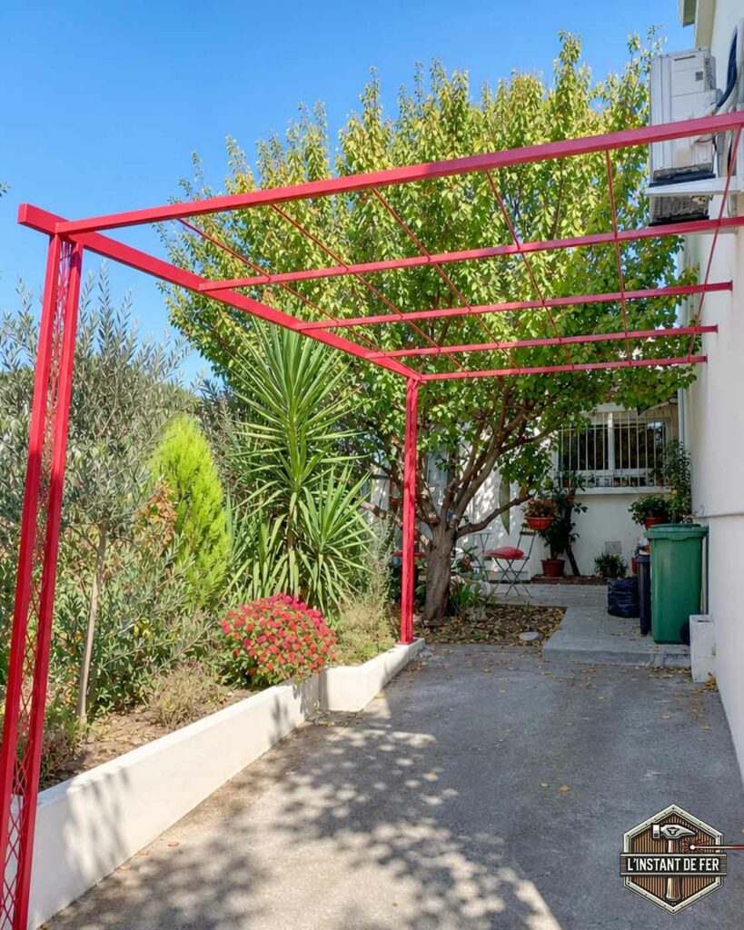 Pergola adossée en acier rouge Pergola adossée sur mesure en acier thermolaqué rouge le long d'une allée