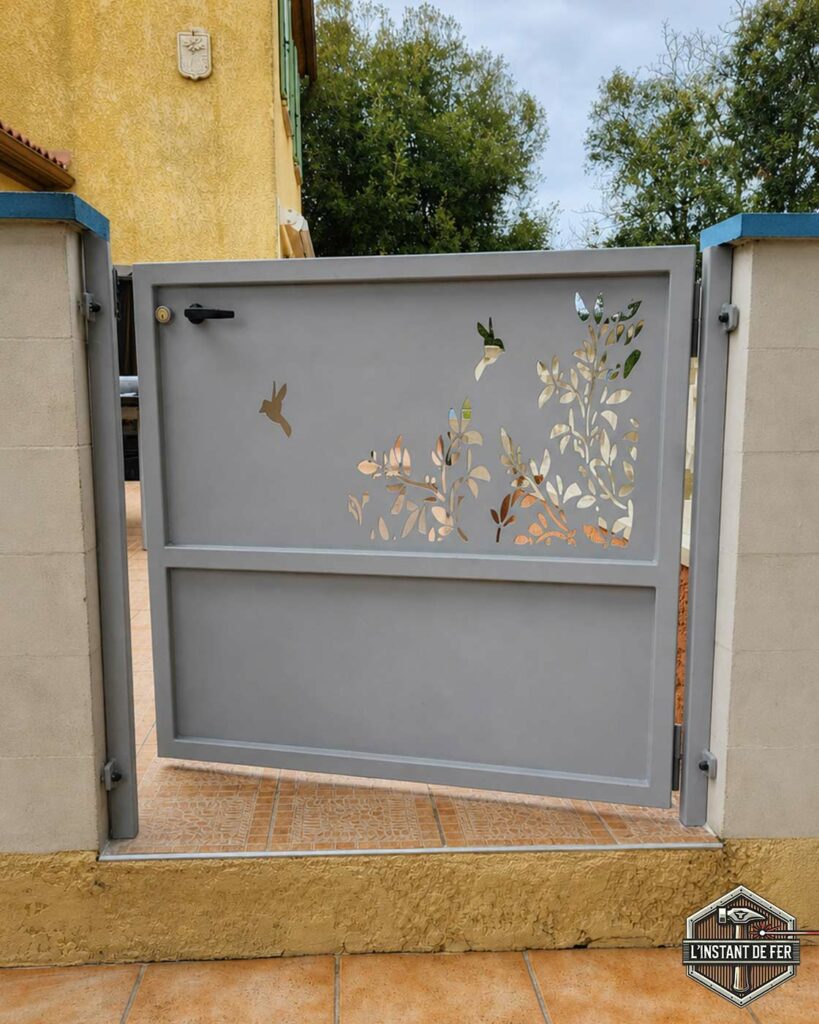 Portillon gris motifs végétaux et oiseaux Portillon sur mesure en acier gris avec motifs feuillage et oiseaux découpés au laser vue côté rue