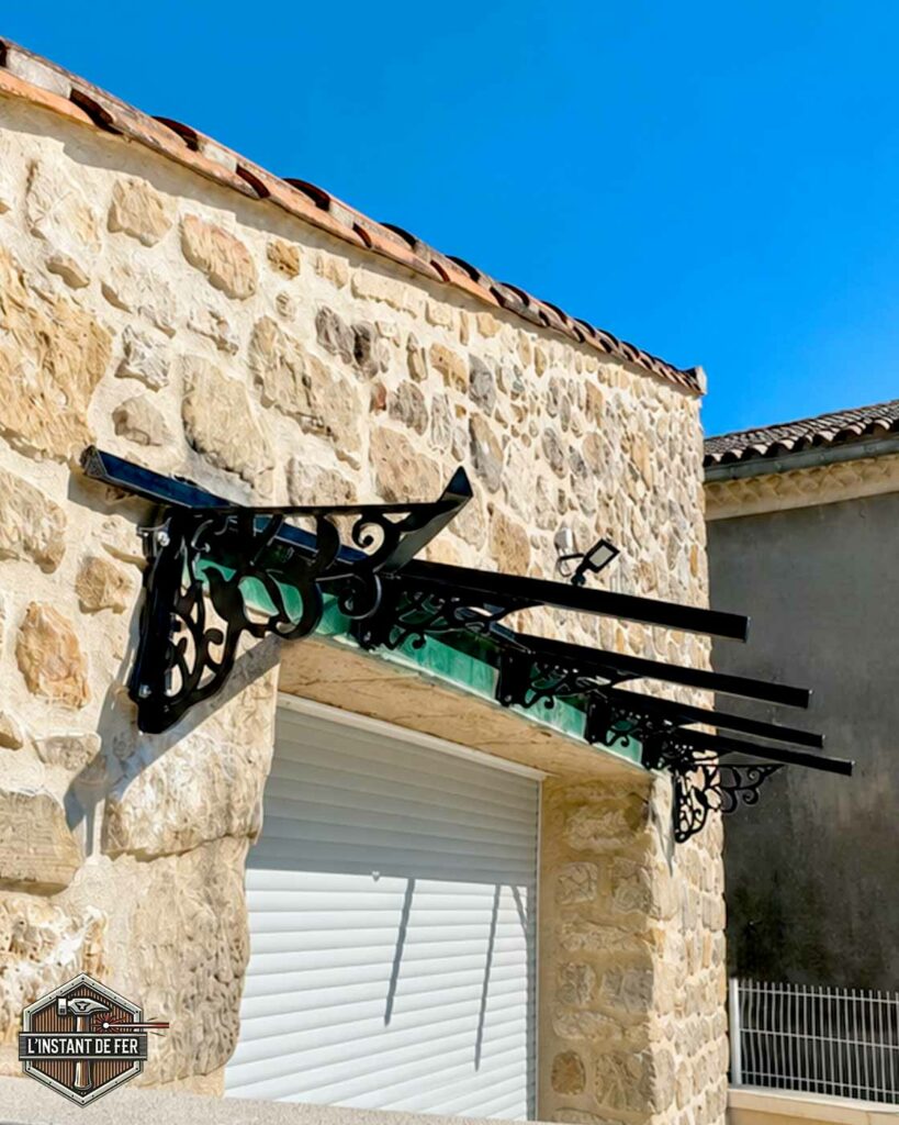 Marquise en acier avec motif découpé au laser Marquise d'accueil en acier avec motif découpé au laser au-dessus d'une porte de garage sur façade en pierre